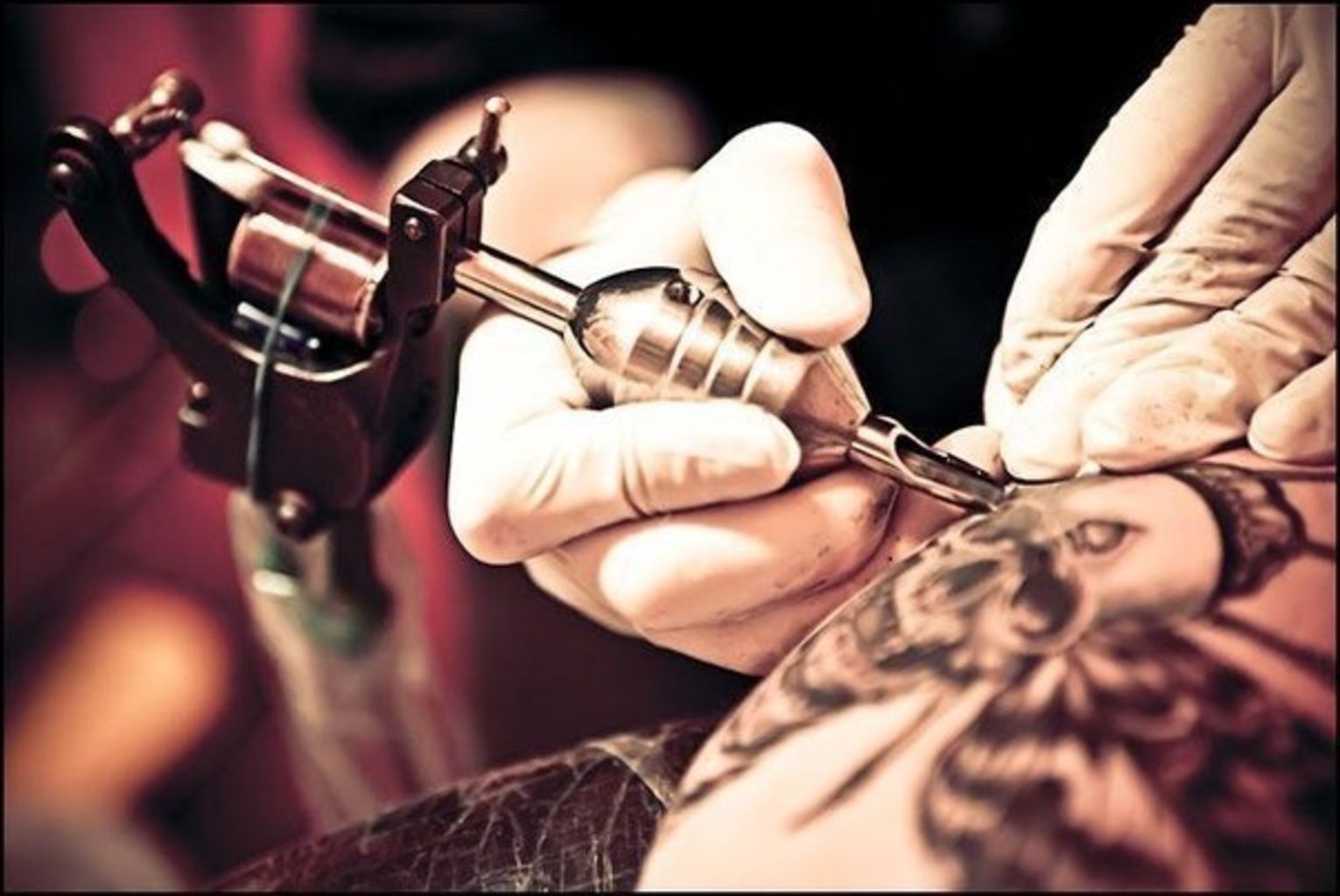 Рука татуировщика с машинкой